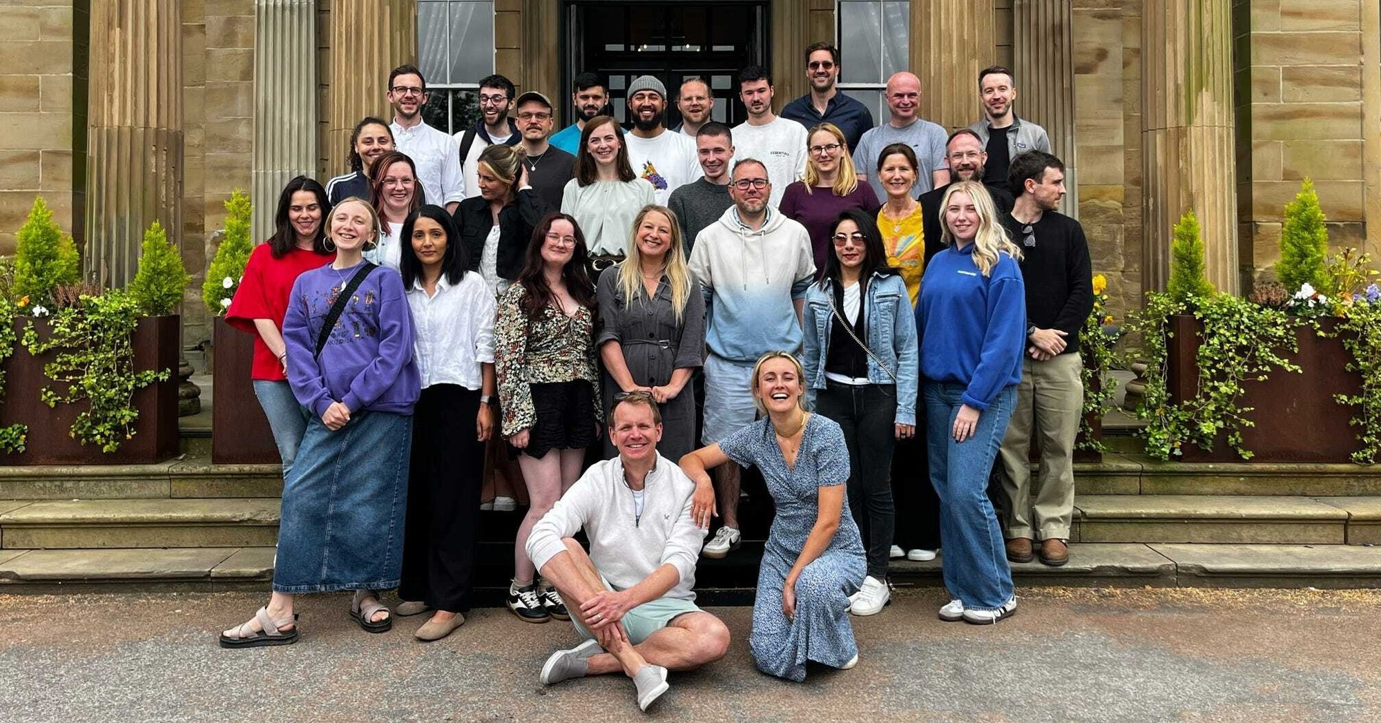 The Little Journey team are stood in a group outside, smiling for a picture
