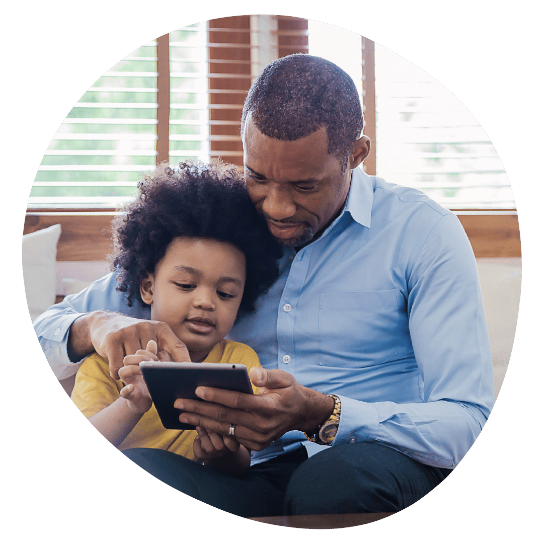 A parent and their child are sat together, both interacting with a tablet.